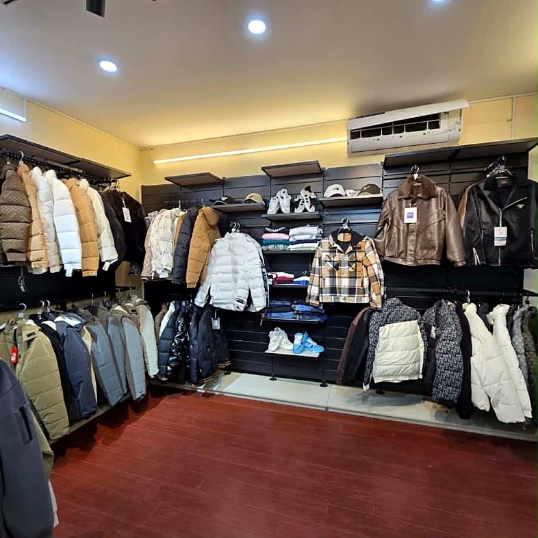 The Sakib showroom: padded jackets on wall rails, leather jackets, and shelves of folded knitwear and trainers