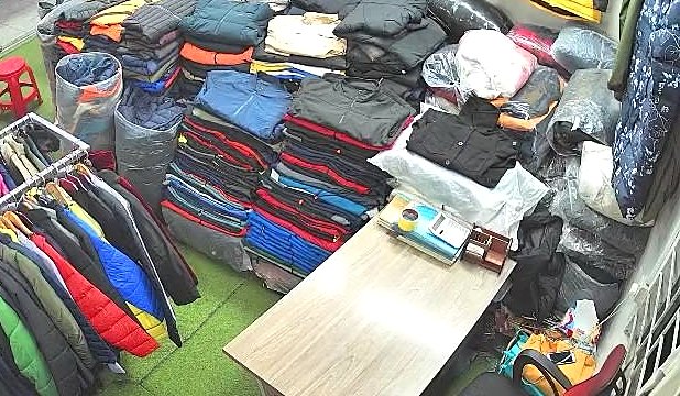 The stockroom: stacks of folded jackets, bagged stock and a rail of hanging coats